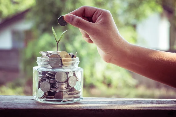 Mano poner monedas de dinero con efecto de filtro estilo vintage retro —  Fotos de Stock