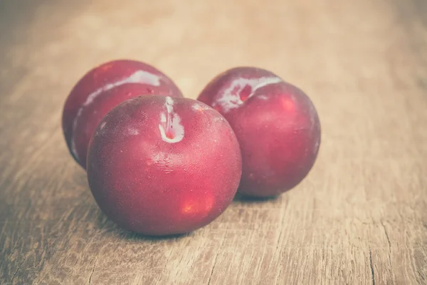 Ciruelas sobre fondo de madera con efecto filtro estilo vintage retro —  Fotos de Stock