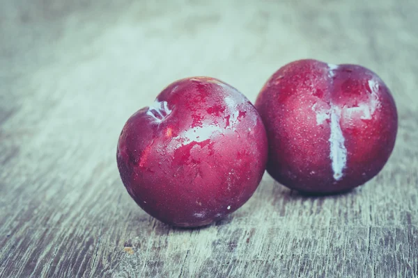 Ciruelas sobre fondo de madera con efecto filtro estilo vintage retro —  Fotos de Stock