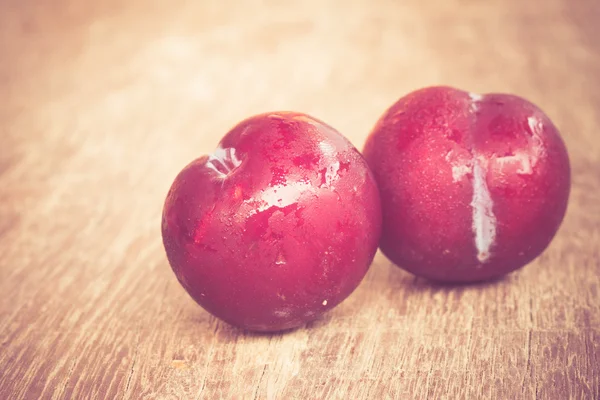 Plums on wood background with filter effect retro vintage style — Stock Photo, Image