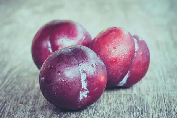 Ciruelas sobre fondo de madera con efecto filtro estilo vintage retro —  Fotos de Stock