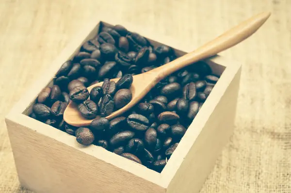 Grãos de café e colher de madeira com efeito de filtro retro vintage s — Fotografia de Stock