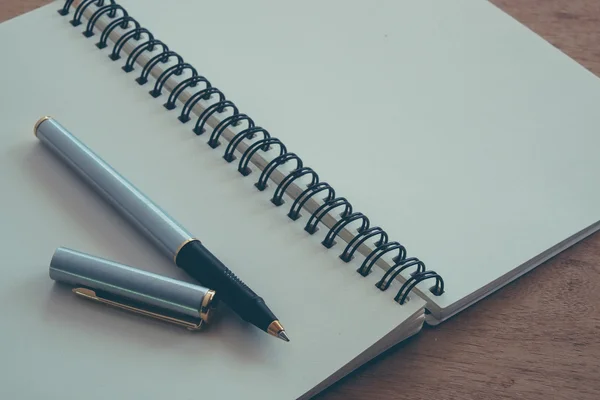 Бумага ноутбук и ручка на столе с эффектом фильтра ретро винта — стоковое фото
