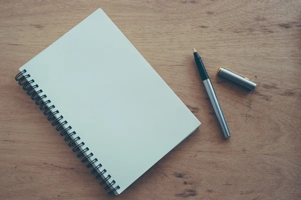 Cuaderno de papel y pluma sobre una mesa con efecto filtro retro vinta —  Fotos de Stock