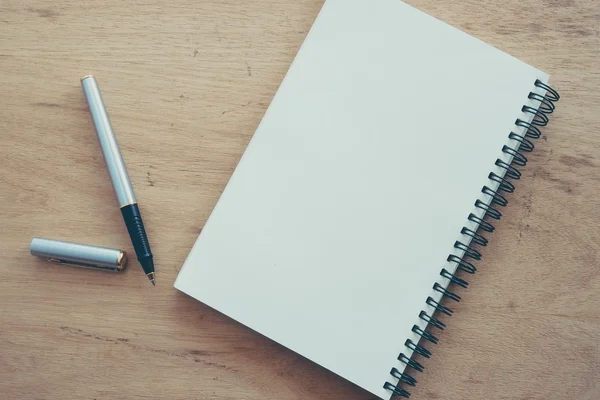 Caderno de papel e caneta em uma mesa com efeito de filtro retro vinta — Fotografia de Stock