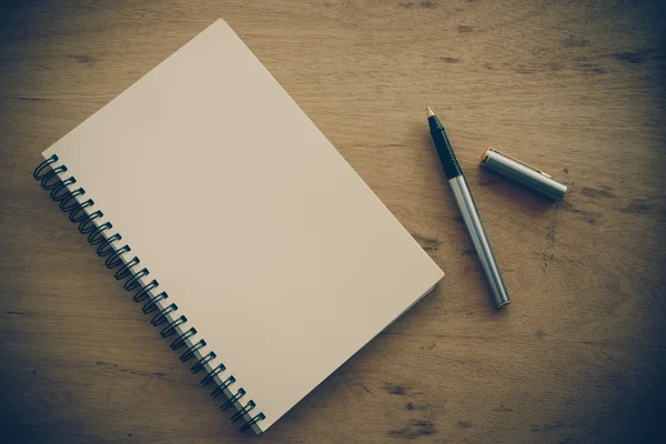 Cuaderno de papel y pluma sobre una mesa con efecto filtro retro vinta — Foto de Stock