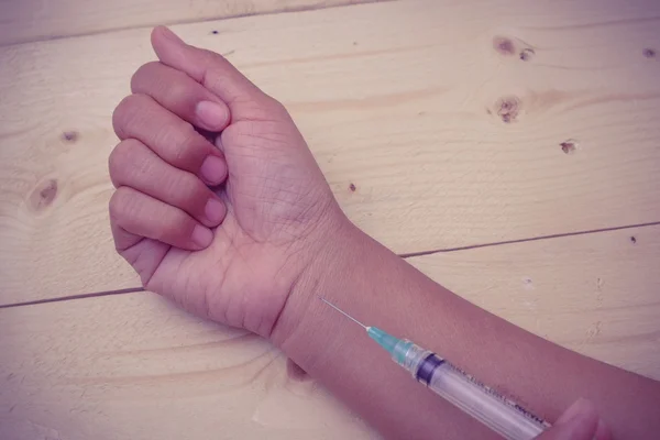 Hand holding syringe with filter effect retro vintage style