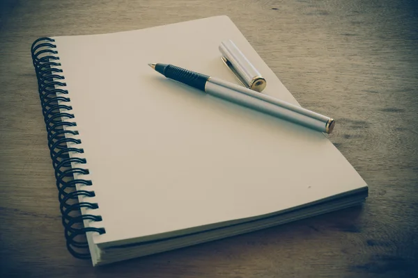 Caderno de papel e caneta em uma mesa com efeito de filtro retro vinta — Fotografia de Stock