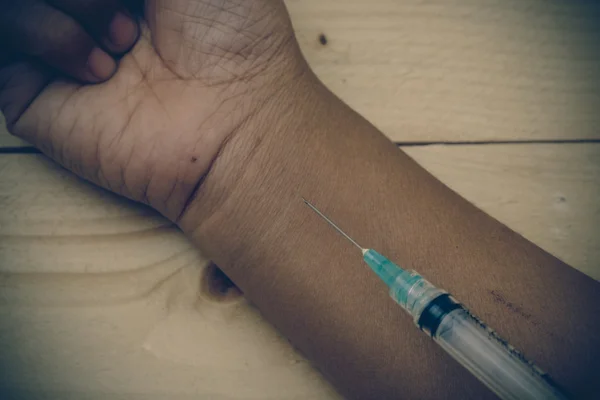 Hand holding syringe with filter effect retro vintage style