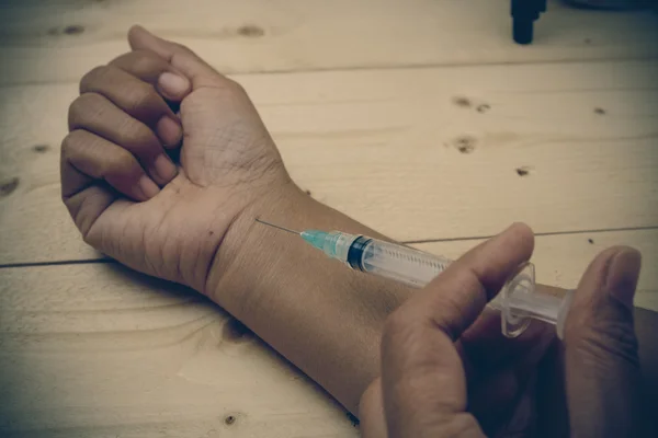 Hand holding syringe with filter effect retro vintage style