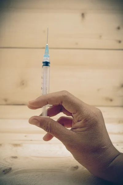 Hand holding syringe with filter effect retro vintage style