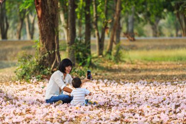 Taking picture of her kid and flowers clipart