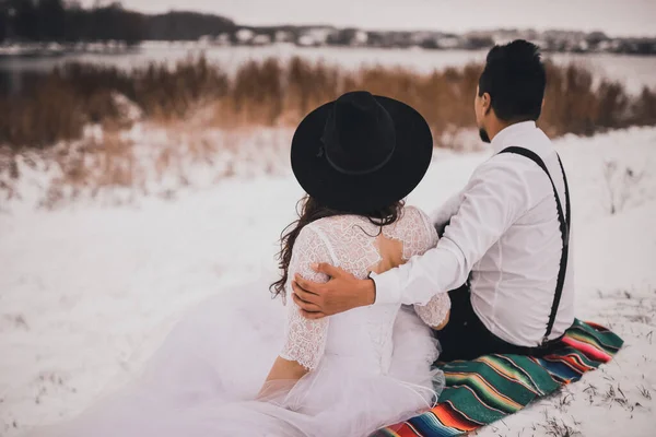 Noivo e noiva sentados em um véu nacional mexicano em uma colina nevada — Fotografia de Stock