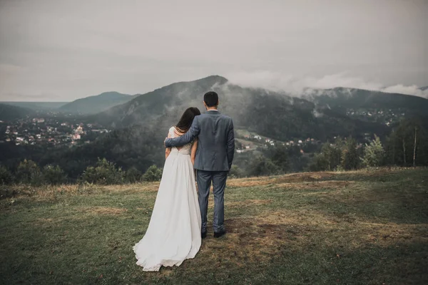 Novia está de espaldas con el novio en las montañas en la niebla —  Fotos de Stock