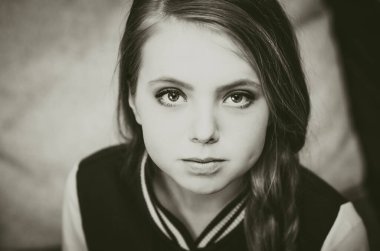 Genç bir kızın doğrudan kameraya bakarken çekilmiş siyah beyaz bir fotoğrafı.