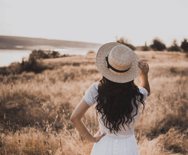 Brunette girl in a white dress with curly hair puts on a boatman hat