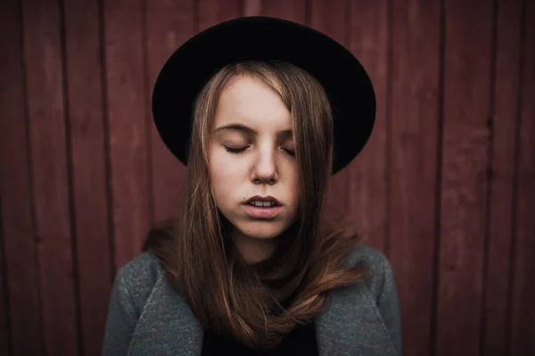 teenager girl with long hair and freckles on face in fashionable black felt hat