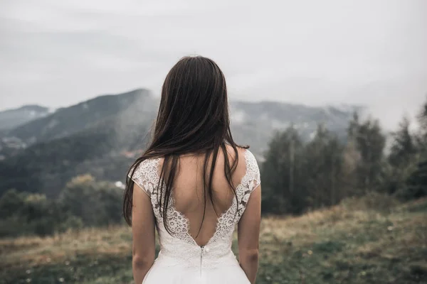 Panna młoda w białej sukni ślubnej z otwartymi plecami w górach — Zdjęcie stockowe