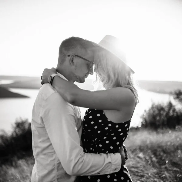 Un homme avec une femme dans un câlin chapeau et baiser dans l'herbe haute dans la prairie — Photo