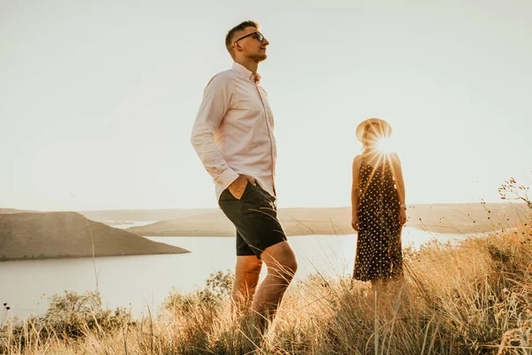 Žena za mužem v paprscích zapadajícího slunce v létě — Stock fotografie