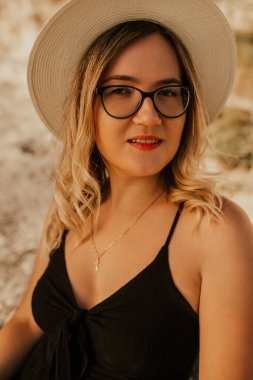 Açık tenli, gözlüklü ve şapkalı bir kadın.
