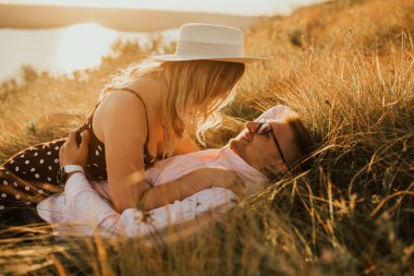 Şapkalı adam ve kadın çimenlerde yatıyor.