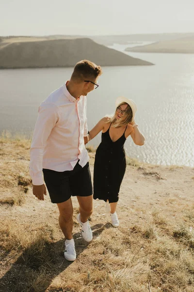 Uomo e donna innamorati camminano su una montagna sopra un grande lago — Foto Stock