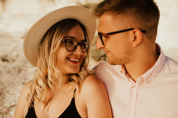 Mann und Frau mit Hut sitzen auf einem großen Steinfelsen Stockbild