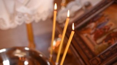 Vaftiz için bir kase kutsal su yanan mumların yanında.