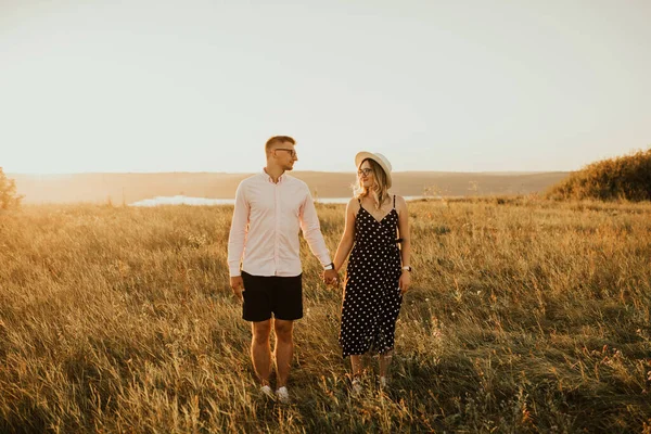 Jongen met een meisje in hoed wandelen in weide — Stockfoto