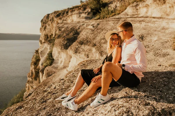 Muž a žena v klobouku sedí na velké kamenné skále — Stock fotografie