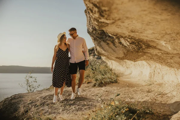 Muž a žena v klobouku procházka podél skal nad útesem — Stock fotografie