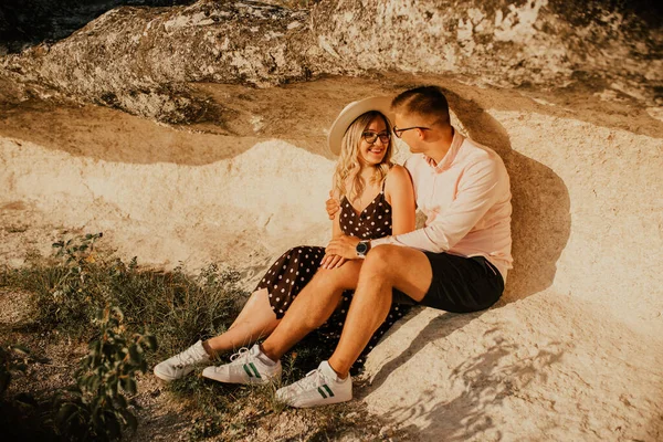 Man en vrouw met hoed zitten op grote stenen rots — Stockfoto