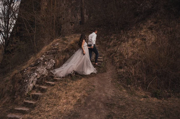 Hombre con mujer embarazada con un gran vientre cerca de la montaña están caminando en escalones de piedra —  Fotos de Stock