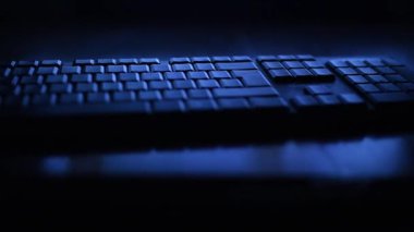 Mavi ışıkta gecenin karanlığında bir bilgisayar klavyesi