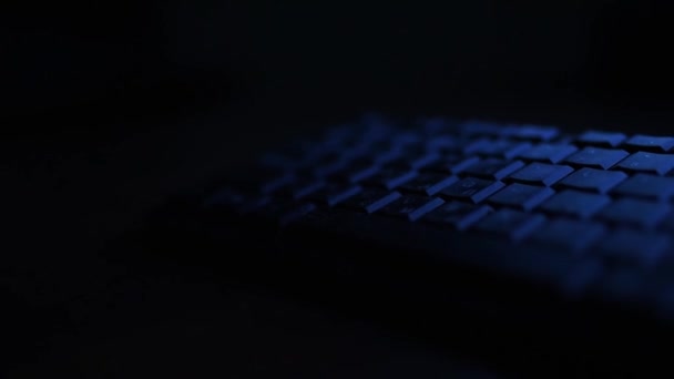 Eine Computertastatur in der dunklen Nacht in blauem LICHT — Stockvideo