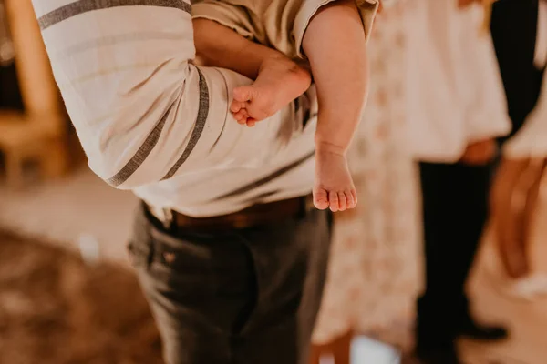 Ноги босоногого малыша крупным планом на руках у крестного отца — стоковое фото