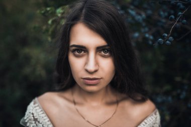 Yeşil yaban mersinlerinin yanında çıplak omuzlu, uzun saçlı bir gelin.