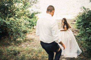 Gelin ve damat gülerek yazın batan güneş ışınlarına karşı birlikte koşarlar. 