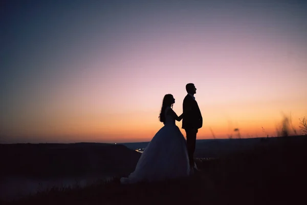 Silhouetten van bruid en bruidegom 's nachts tegen meer en eilanden — Stockfoto