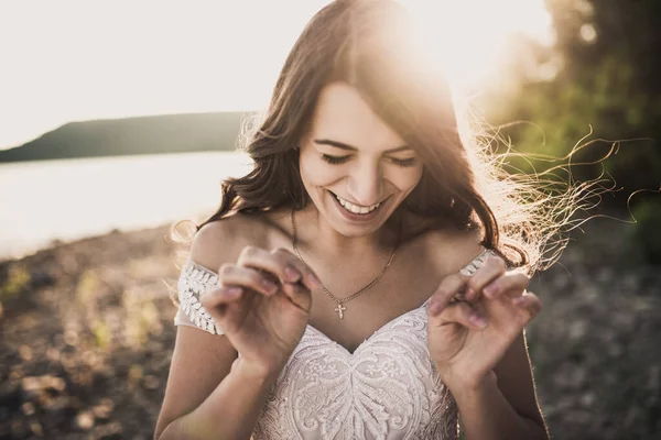 Braut im Brautkleid glücklich und lachend gegen Sonnenstrahlen im Sommer — Stockfoto