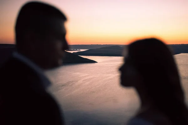 Silhouetten von Braut und Bräutigam bei Nacht vor See und Inseln lizenzfreie Stockbilder