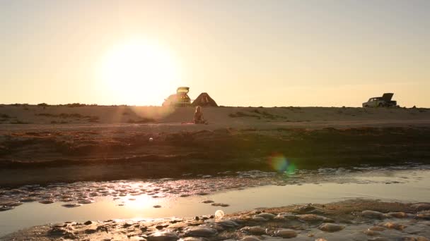 Donna in costume da bagno bikini con i capelli lunghi corre lungo la riva del mare contro il sole al tramonto — Video Stock