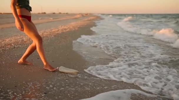 La donna butta la spazzatura in acqua. onde del mare hanno portato rifiuti rifiuti di plastica sulla costa sabbiosa — Video Stock