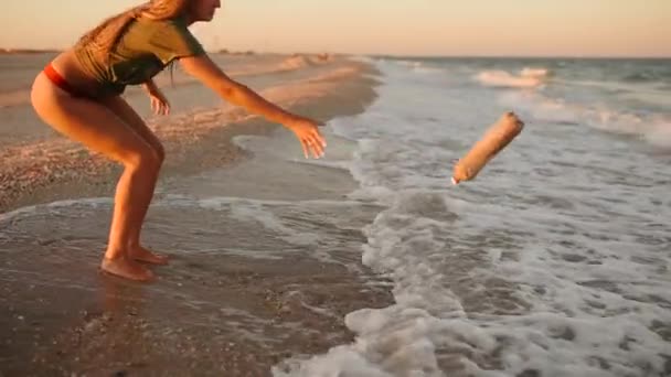 La donna butta la spazzatura in acqua. onde del mare hanno portato rifiuti rifiuti di plastica sulla costa sabbiosa — Video Stock