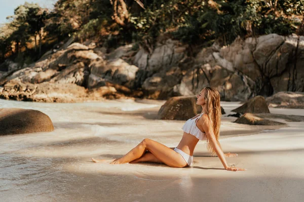 ヨーロッパの女性で白いビキニ水着オンビーチ座ってオン砂のビーチ — ストック写真