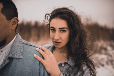 Kot ceketli Meksikalı adam büyük boy ve kadın gülüşerek sarılıyor. Damat ve gelin, kışın karda aşık olurlar. şık bir parti elbisesi. 2021.