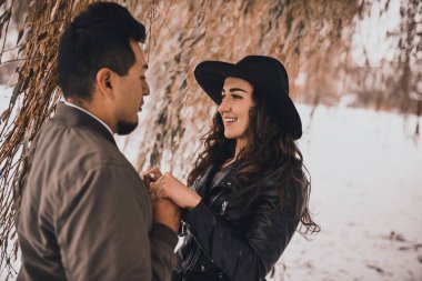 Meksikalı adam Ukraynalı bir kadının elini tutuyor. Siyah deri ceketli ve kışın siyah şapkalı. Farklı milletler arasındaki aşk Halkların Dostluğu