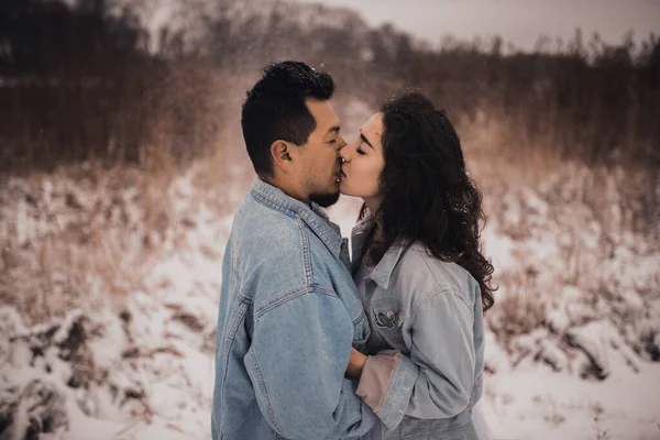 身穿超大斜纹棉布夹克的墨西哥拉美裔男子和正在亲吻拥抱笑的女人 新郎和新娘在冬天的雪地里结为夫妻 2021年时尚派对婚纱 — 图库照片