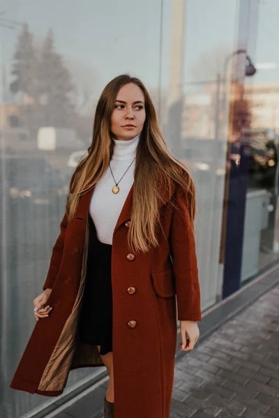 Kvinna i höst kläder promenader på gatan bakgrund skyltfönster Stockfoto